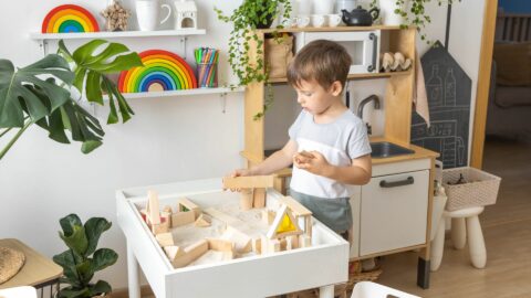 Child playing with wooden building blocks in a playroom